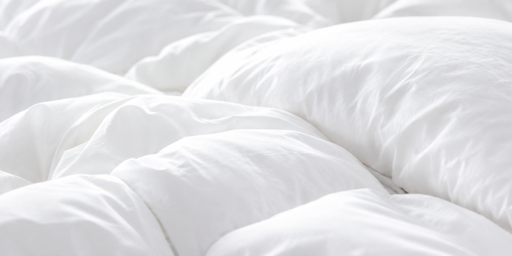 Oreiller blanc posé sur un lit avec une literie blanche